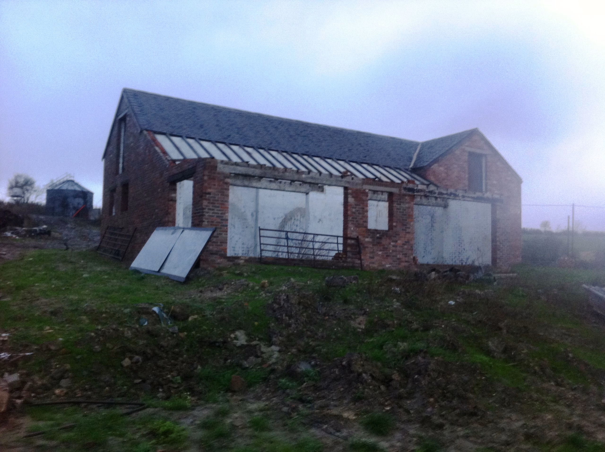 A derelict barn at Hill Farm before conversion, with blocked-up openings and a corrugated lean-to