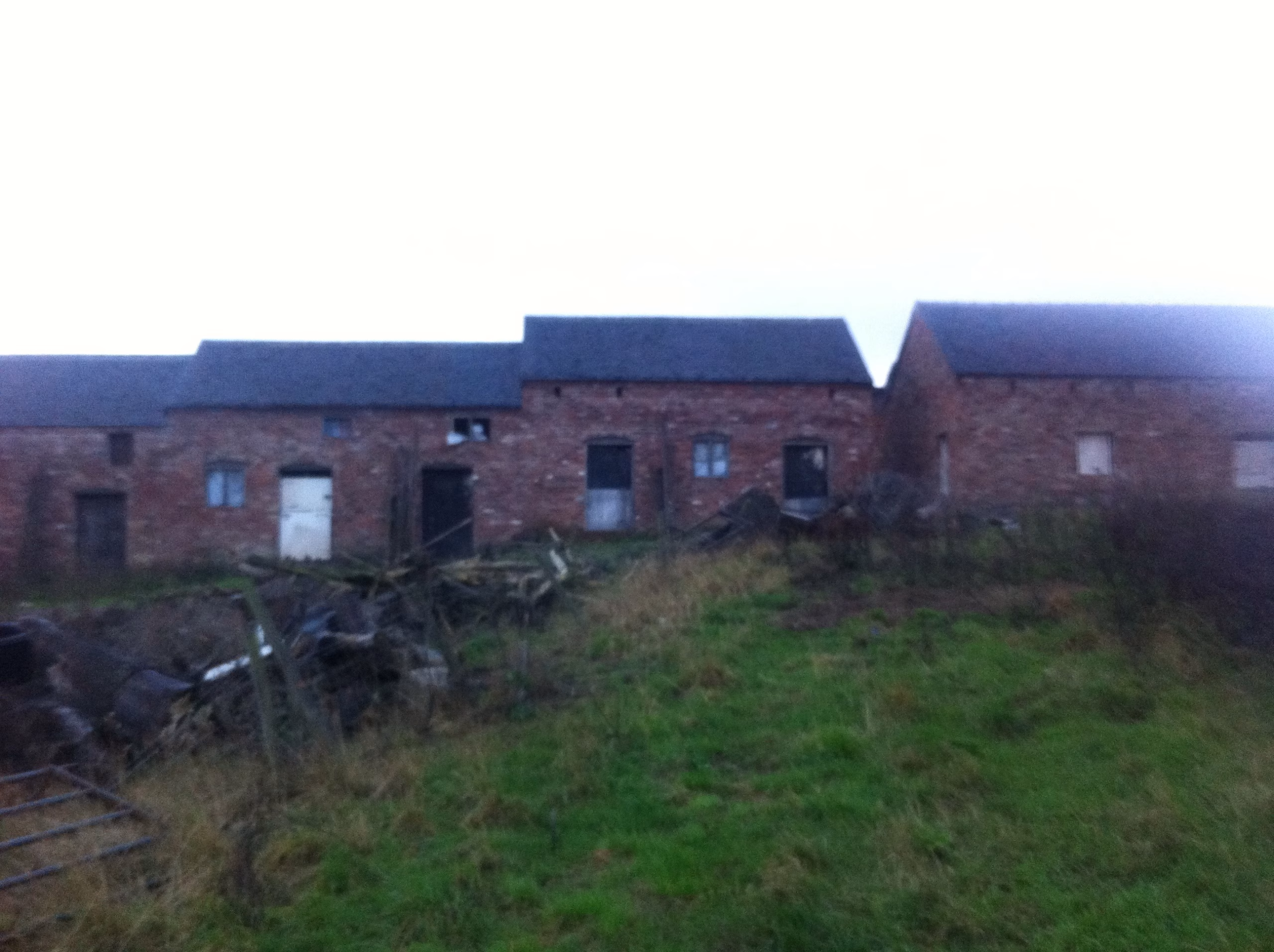 The barn range at Hill Farm before restoration &mdash; derelict brickwork, boarded openings and overgrown ground